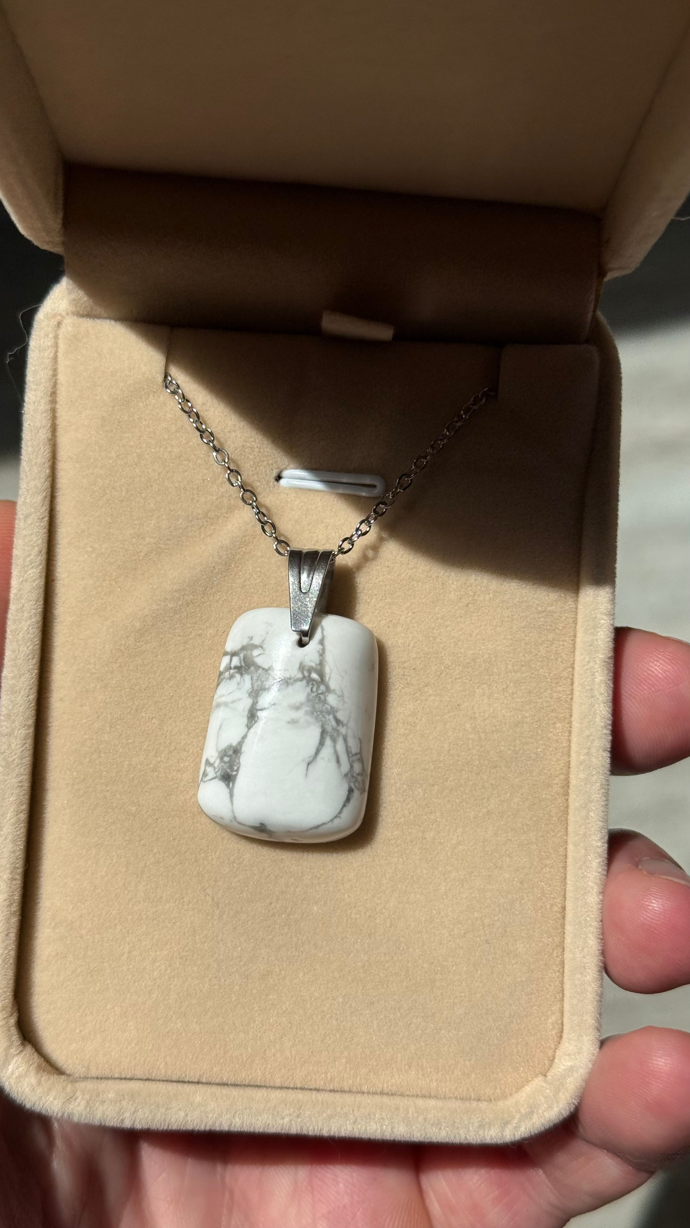 Collier avec pendentif en pierre blanche dans son écrin