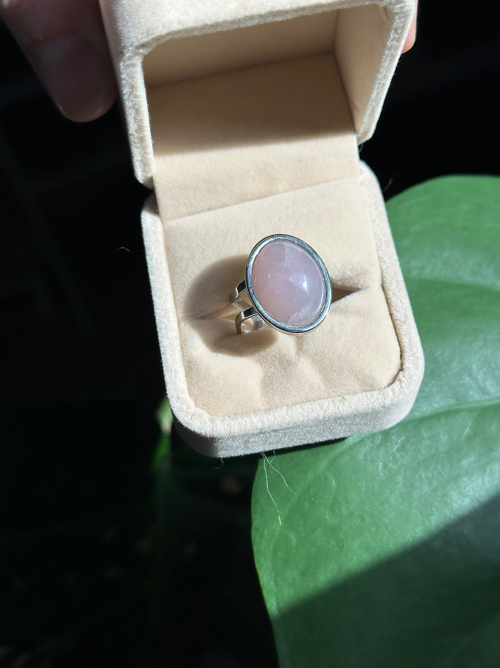 Bague en Quartz Rose – Amour, douceur et harmonie, placée dans un écrin beige avec une feuille verte.