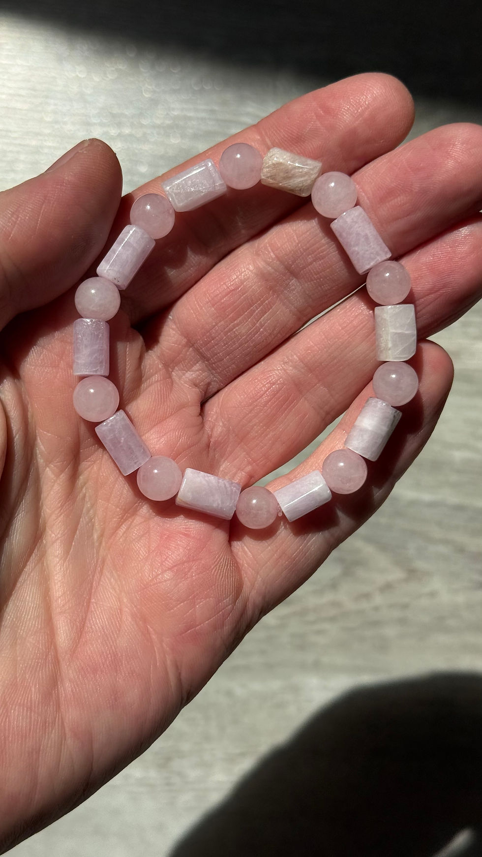 Bracelet artisanal en pierres roses dans le creux d'une main