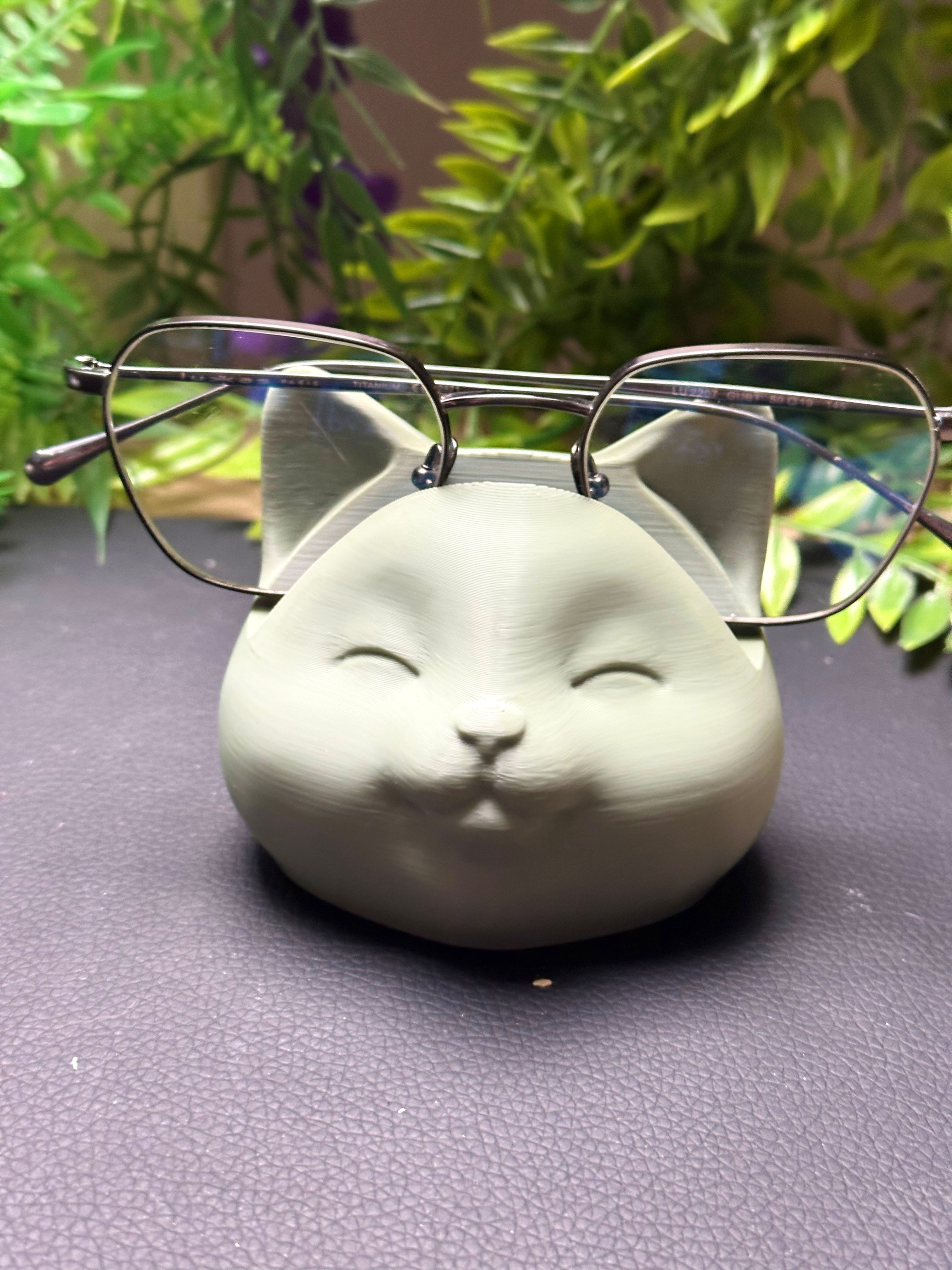 Support de lunettes en forme de chat gris avec des lunettes rondes.