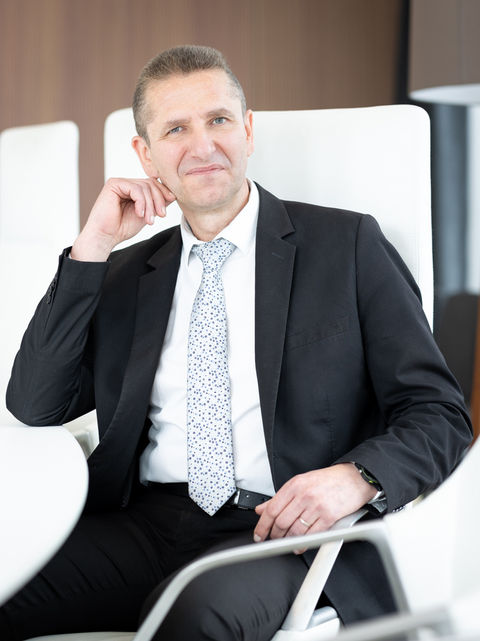 Portrait d'un homme en costume noir assis, posant avec une expression réfléchie.