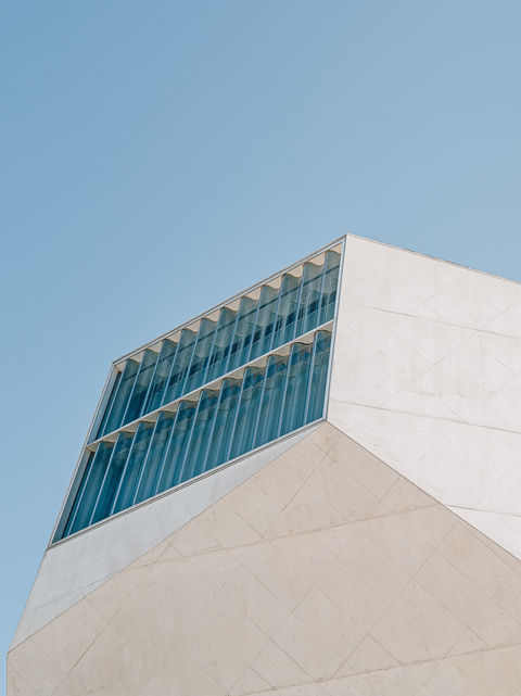 Casa da Música - Porto. Architecture angulaire blanche avec une fenêtre en verre inclinée, contrastant avec le ciel bleu.