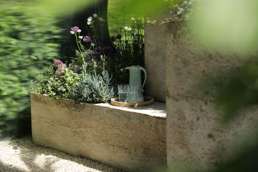 a pitcher and two glasses sit on a tray in a garden