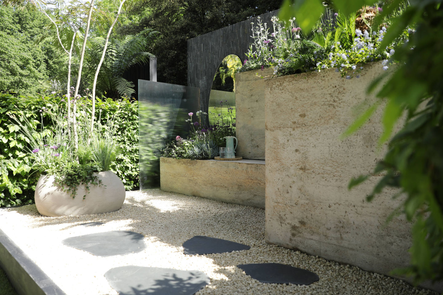 a garden with a concrete structure surrounded by gravel and flowers