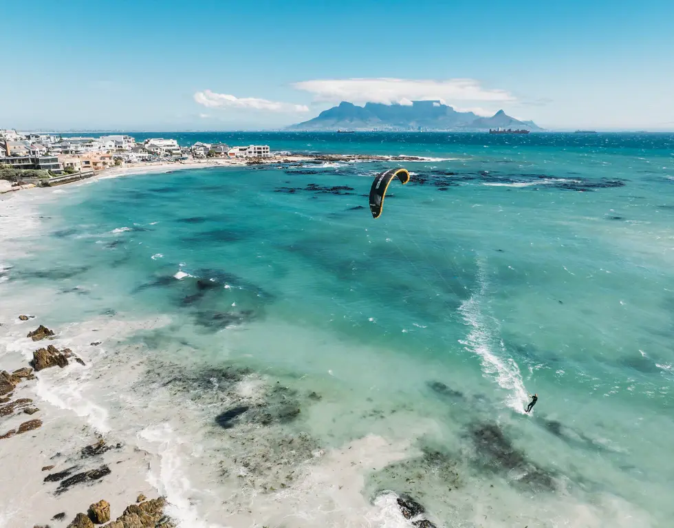 Kitesurfer soaring over turquoise waters near Table Mountain