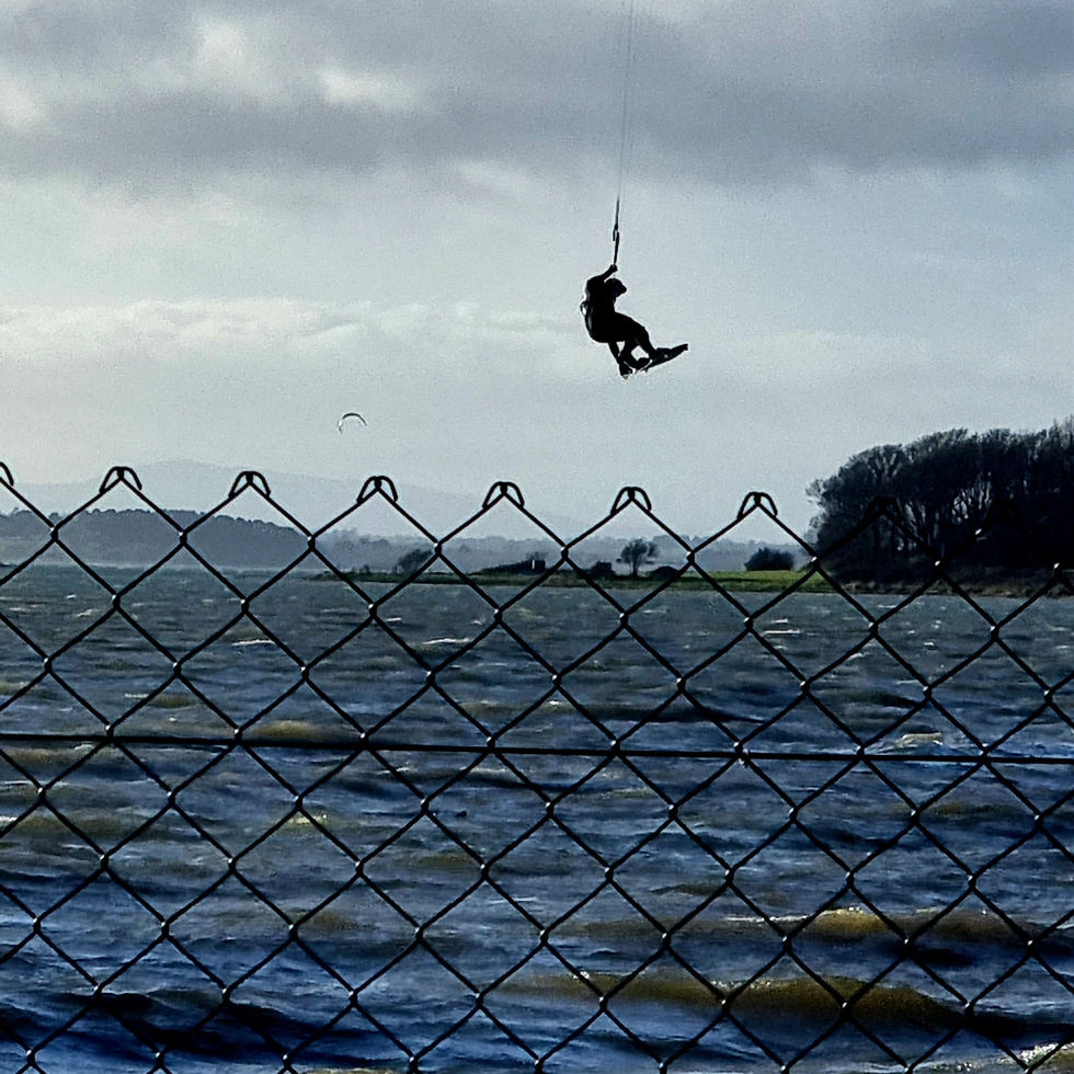 Kitesurfer soaring over wavy water
