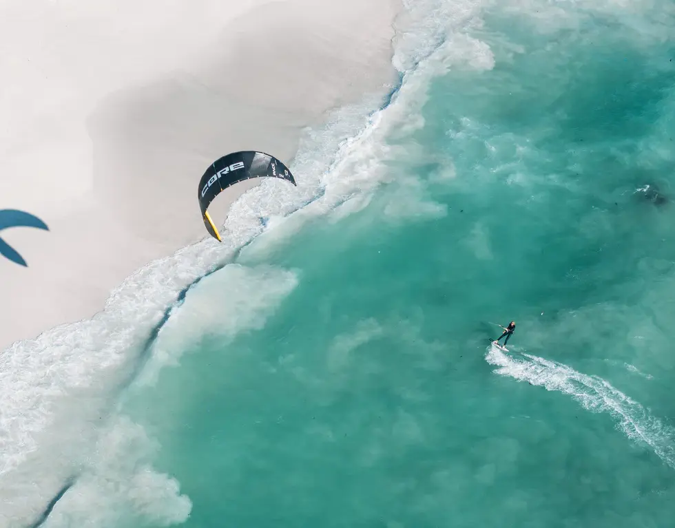 Aerial view kitesurfer riding turquoise waves