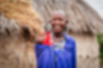 A Maasai woman smiling outside her Maasai house in Tanzania