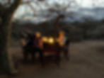 Tourist having dinner by oil lamp light in a remote Lake Eyasi savanna camp during a multi-day Hadzabe cultural experience in Tanzania.