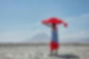 A Maasai man with a red shuka draped over his head gazes toward the sacred Ol Doinyo Lengai mountain in Tanzania.