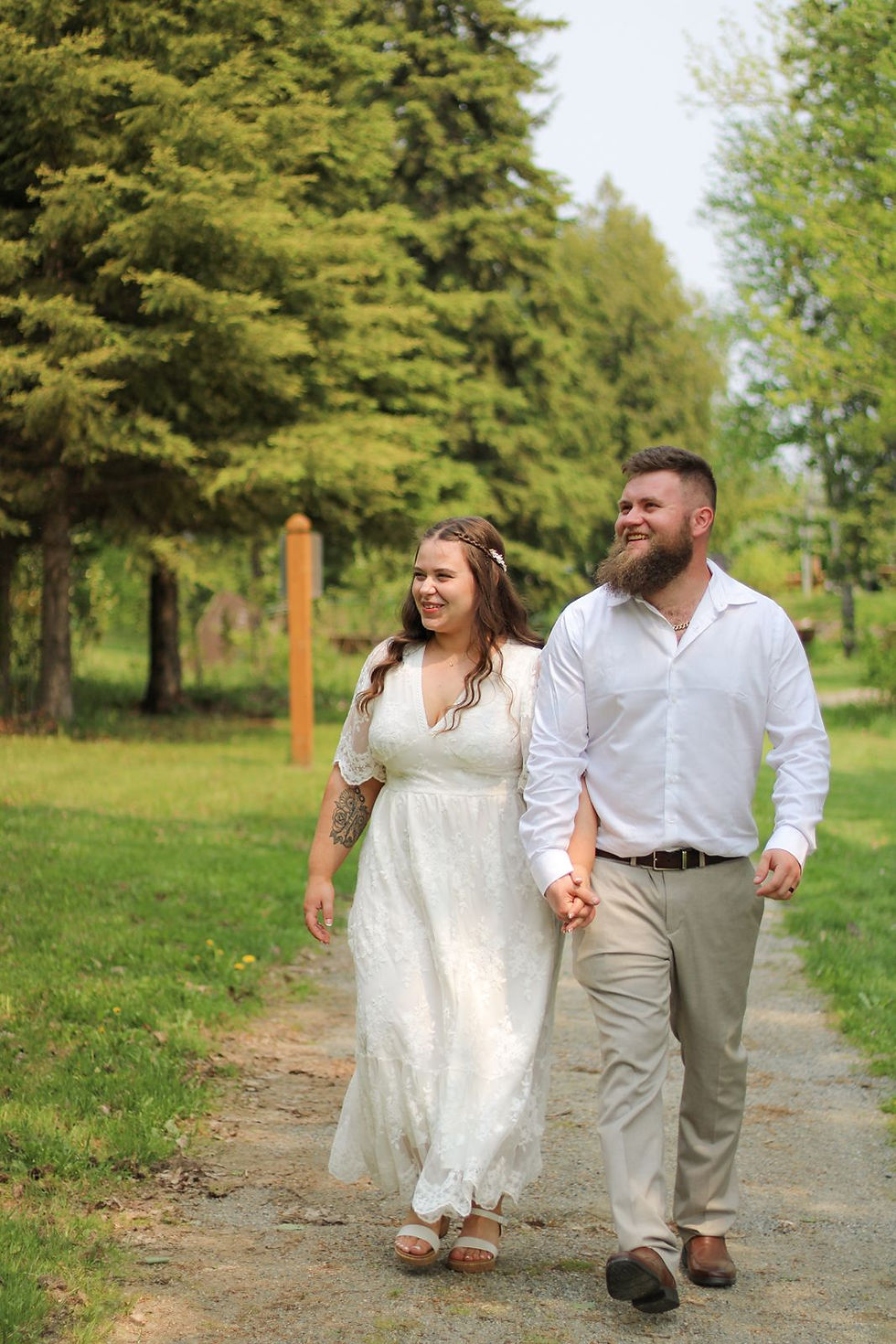 A joyful, candid shot of a couple walking hand-in-hand along a sunlit forest path