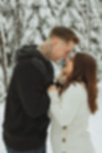 Winter forest background with a couple smiling and looking in each others eyes