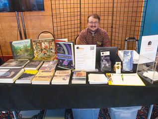Micah behind table selling books from Friends of Minidoka's bookstore