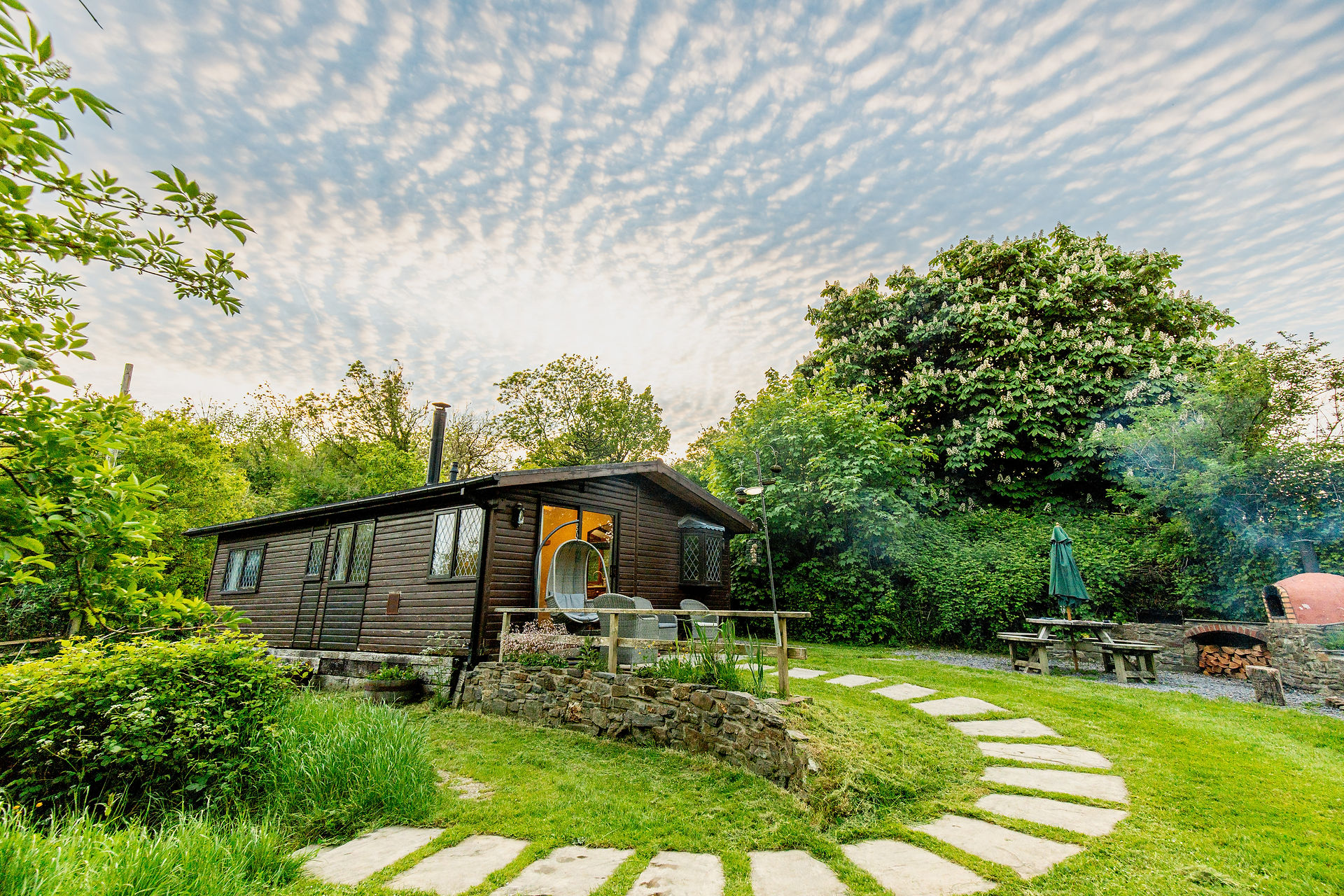 The Chestnut Cabin in the summer sunshine, green and luscious grounds
