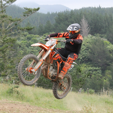 Orange motorbike making a jump on the trail on the Hikurangi rural trail ride