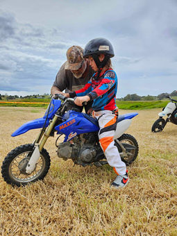 a child being shown how to brake at the learn to ride motorbike track