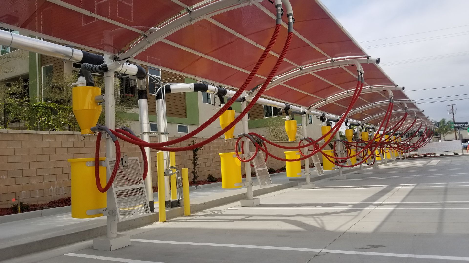Car wash bays with red hoses under a red awning.