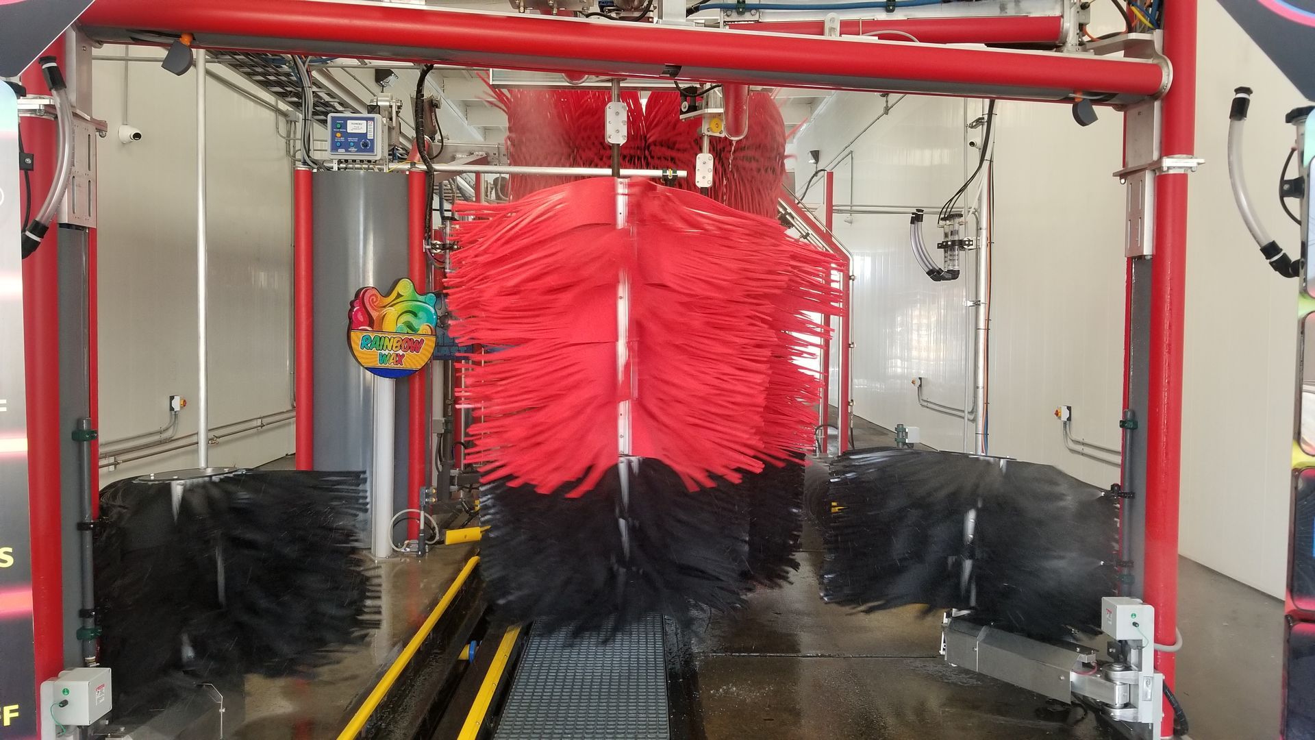 Car wash interior with red and black brushes.