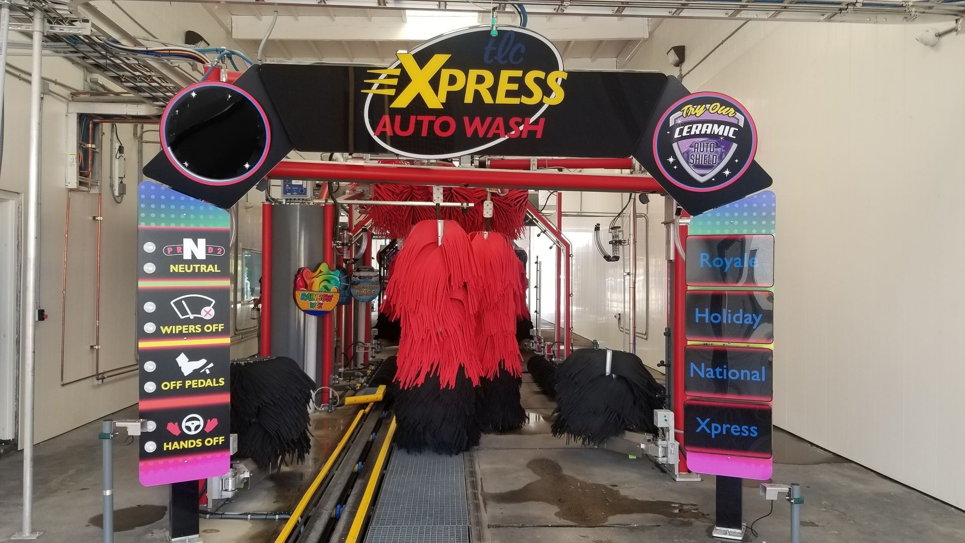 Car wash with red brushes, a conveyor belt, and TLC Express Auto Wash signage