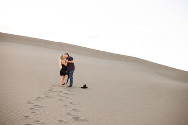 Couple in black kissing on the sand dunes outside of Mountain Home, Idaho for a golden hour session with Summit & Sage Photography.
