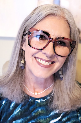 A mature woman with shoulder-length grey hair and large-rimmed glasses smiles warmly at the camera; it is the founder and owner of Validity Counselling in Prince George, BC: Jenny DeReis. Jenny has a Master's degree in Counselling Psychology and specializes in Dialectical Behavioral Therapy (DBT), Borderline Personality Disorder (BPD), and Couples Counselling.