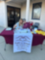 Two women at an event table with a Faith in Action banner