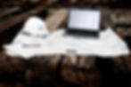 Laptop displaying blueprints, hard hat, and documents on wood: Executive Interiors construction site