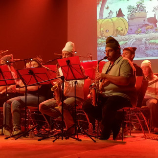 Pfiou… Après une journée de route, une journée de paperasse et de boulot, il était temps de vous faire un retour sur cet incroyable week-end de spectacle musical que nous avons pu vivre grâce à l’équipe de La Boressoise ! On ne cessera de le dire, mais MERCI à toute l’équipe (Joël, Alexa, Éric, Christophe, JB, tous les musiciens, chanteurs, encadrants, techniciens, comédiens, et tous les enfants qui ont participé à ce spectacle)… Il faut quand même se dire que c’est complètement fou ! En 2025, lors du festival du FLIP à Parthenay, Joël Chaumat découvre notre BD alors que Guillaume Albin était en dédicace, et nous propose quelques mois plus tard de lancer le spectacle musical de fin d’année de son école de musique (La Boressoise) à Albon (26) sur le thème des Shpunks !! Évidemment, nous avons dit un grand OUI ! Ça n’arrive jamais, dans une vie d’auteurs de BD, qu’un événement pareil se produise… (Ou alors pour de grands classiques installés dans le paysage culturel depuis des décennies.) Mais nous, nous en sommes à notre premier album ! Cela fait à peine quelques mois qu’il est sorti après un crowdfunding et une petite distribution. Alors durant tous ces mois, toute l’école a bossé d’arrache-pied pour coller à l’univers tout en se l’appropriant, en créant une histoire reprenant l’origin story des Chooms et des Shpunks, ainsi que l’atmosphère de polar futuriste humoristique avec les enquêtes de Clifford Shpunk, notre héros détective. Ils ont aussi eu la gentillesse de nous intégrer au processus de création : à la fois pour ne pas faire d’erreur dans l’univers, mais aussi pour nous consulter sur des choix musicaux que nous aimerions voir apparaître. Nous avons pensé à des atmosphères cabaret, polar, gangster… et en sont sortis des thèmes comme Chicago, Cowboy Bebop ou encore les Blues Brothers, ainsi que de nombreuses autres musiques de pop, variété, classiques et bandes originales de films… Nous avons aussi aidé sur certains visuels projetés en arrière-plan et pour l’affiche, avec des dessins originaux réalisés spécialement pour le spectacle (les Chooms et Shpunks musiciens notamment), quelques vidéos et des extraits de la BD elle-même pour appuyer l’ambiance. Et franchement… que dire de ce week-end ? Ça y est, le dimanche 10 mai, c’était le jour J ! Nous avons tout d’abord été très chaleureusement accueillis par l’équipe dans une ambiance vraiment super sympa de franche camaraderie… et ça faisait plaisir de voir tout l’engouement et l’investissement des participants à tous les niveaux ! Après une très sympathique séance de dédicaces à la librairie “@Des Saveurs et Des Mots”, nous avons participé aux répétitions puis, le lendemain, à la grande représentation ! Environ 200 personnes dans le public, et sur scène une trentaine de musiciens : cordes, piano, cuivres, flûtes, guitares, percussions, chants ! Et une super animation scénique avec des comédiens (mille bravos à Éric, Christophe et Olivia !!) qui ont incarné avec brio tous les personnages : Chooms, Shpunks, ainsi que des humains de toutes les époques, dans des scénettes inspirées de la BD et bourrées d’humour Et il y avait aussi tous les enfants qui se sont éclatés à jouer les p’tits Chooms et Shpunks ! C’était vraiment touchant de les voir connaître l’histoire et les personnages par cœur, avoir déjà leurs préférés et nous demander la suite !! Vraiment un très grand merci à tous pour cette expérience incroyable. En tant qu’auteurs, c’est quelque chose de fabuleux de voir son œuvre reprise, prendre vie, être réappropriée et interprétée par d’autres artistes… Un grand bravo aussi à tous pour avoir supporté et fabriqué ces bonnets shpunkesques (à l’envers ) Bientôt des vidéos de l’événement et d’autres photos… et nous diffuserons aussi MOULTES dessins réalisés par Guillaume lors de l’événement pour anticiper les dédicaces d’après-concert. Merci à toute La Boressoise et à très bientôt !