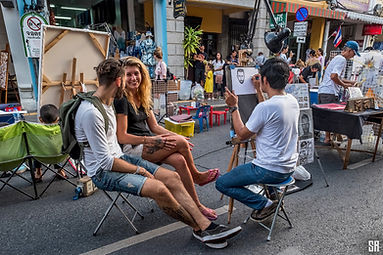 A young couple has their portrait drawn in the street