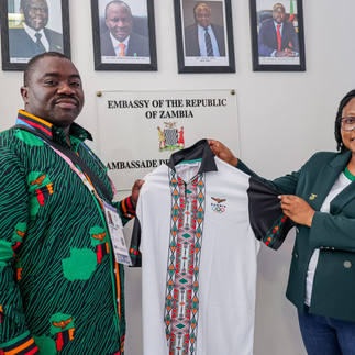 Foloko (L) presenting a Team Zambia Shirt to Twaambo Muzyamba- Charge d‘affaires who received on behalf of the Ambassador Her Excellency Ms. Judith Mulenga
