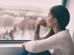 A women in a white sweater staring outside at a snowy scenery
