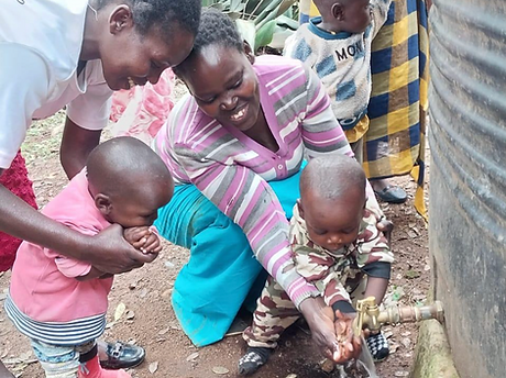 Group of Kenyan mothers and children around a water spickett