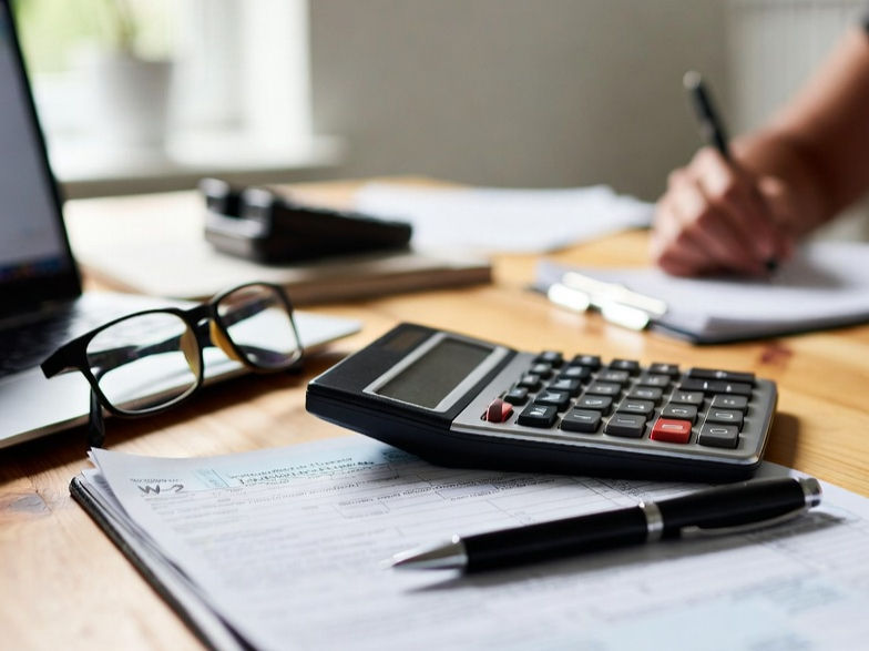 Desk with calculator, pen, and tax documents representing thoughtful tax planning and financial analysis