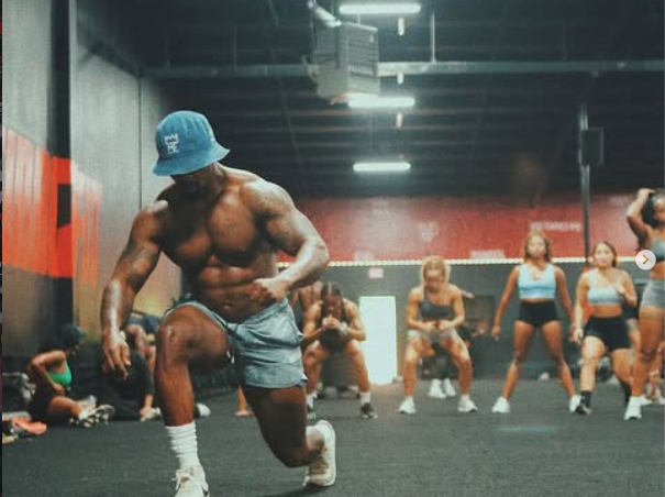 Man performing a lunge in a group gym workout.