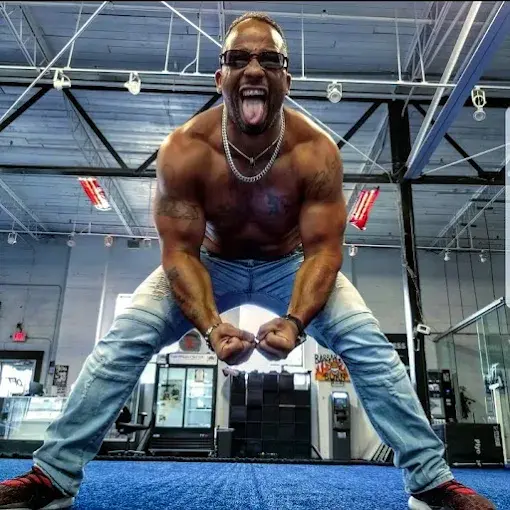 Muscular man, shirtless, glasses, tongue out in gym