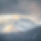The sun peaking out of the clouds over a snowcapped mountain..jpg
