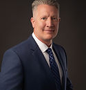 Professional headshot of a man in a blue suit and tie.