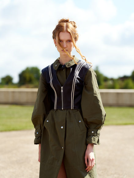 Vrouw in olijfgroene oversized jas in een buitenomgeving