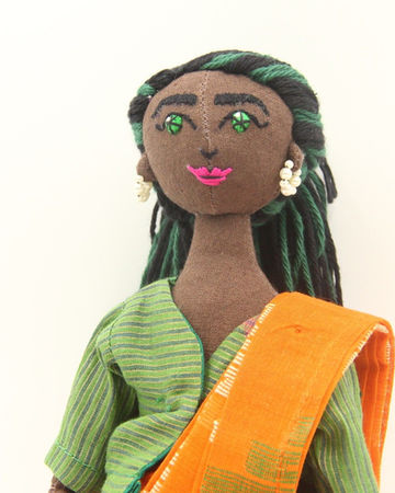 Masakali doll with a deep skin tone, green embroidered eyes and green yarn hair