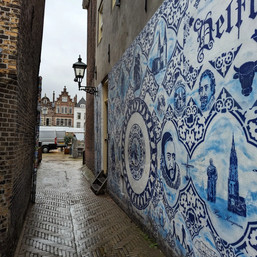 קיר עם דמויות של אנשים בסמטה בעיר העתיקה של דלפט בהולנד