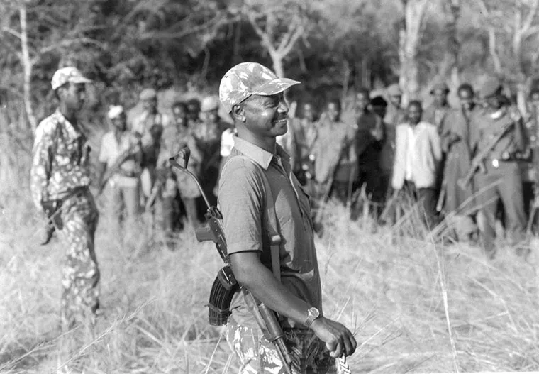 Museveni addresses a group of "Kadogo" children in camouflage outfits standing in rows outdoors. Moo