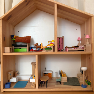Wooden dollhouse interior with tiny furniture, beds, table, chairs, and lamps; colorful rooms look tidy and cozy.