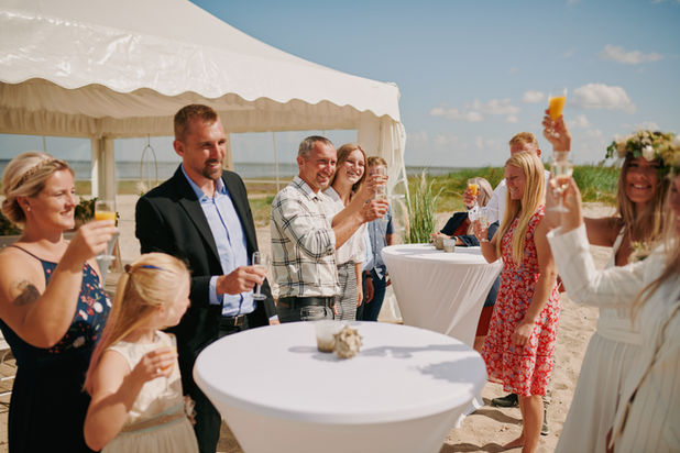 Gruppe Menschen stoßen am Strand mit Sekt an