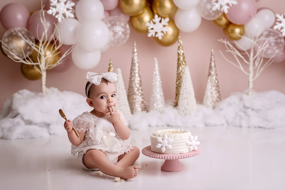 Delightful winter-themed smash cake session with a baby surrounded by pink, white, and gold decor and whimsical snowflakes.