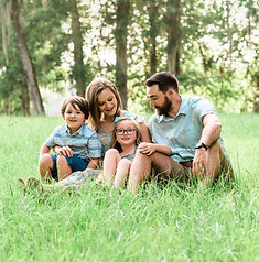 Family of four sitting in tall grass during a Montgomery, AL family photo session