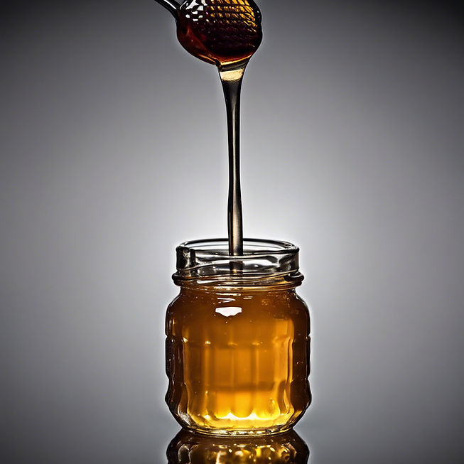 honey dripping from a jar onto a silver spoon black background.jpg