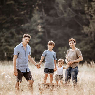 Family photographer Lucerne Central Switzerland - family stands in the tall grass.jpeg