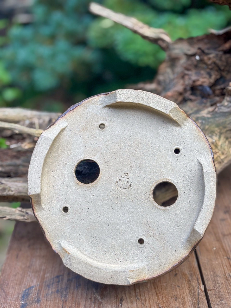 Showcase of a handmade bonsai pot with a brown glaze with blueish detail and drainage holes
