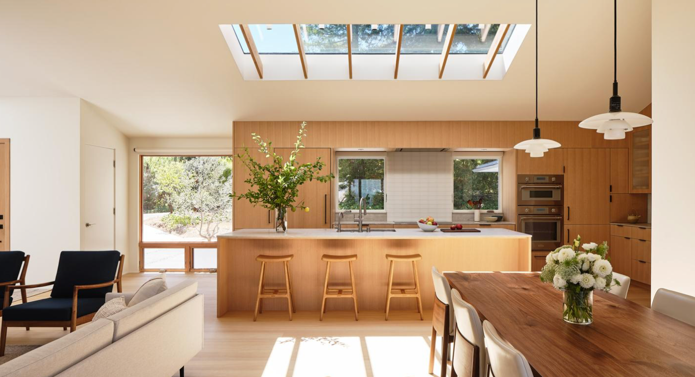 Warm, sunlit oak kitchen and dining area with a large island and skylights