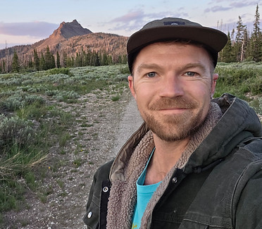 Man in a cap outdoors with mountains in the background